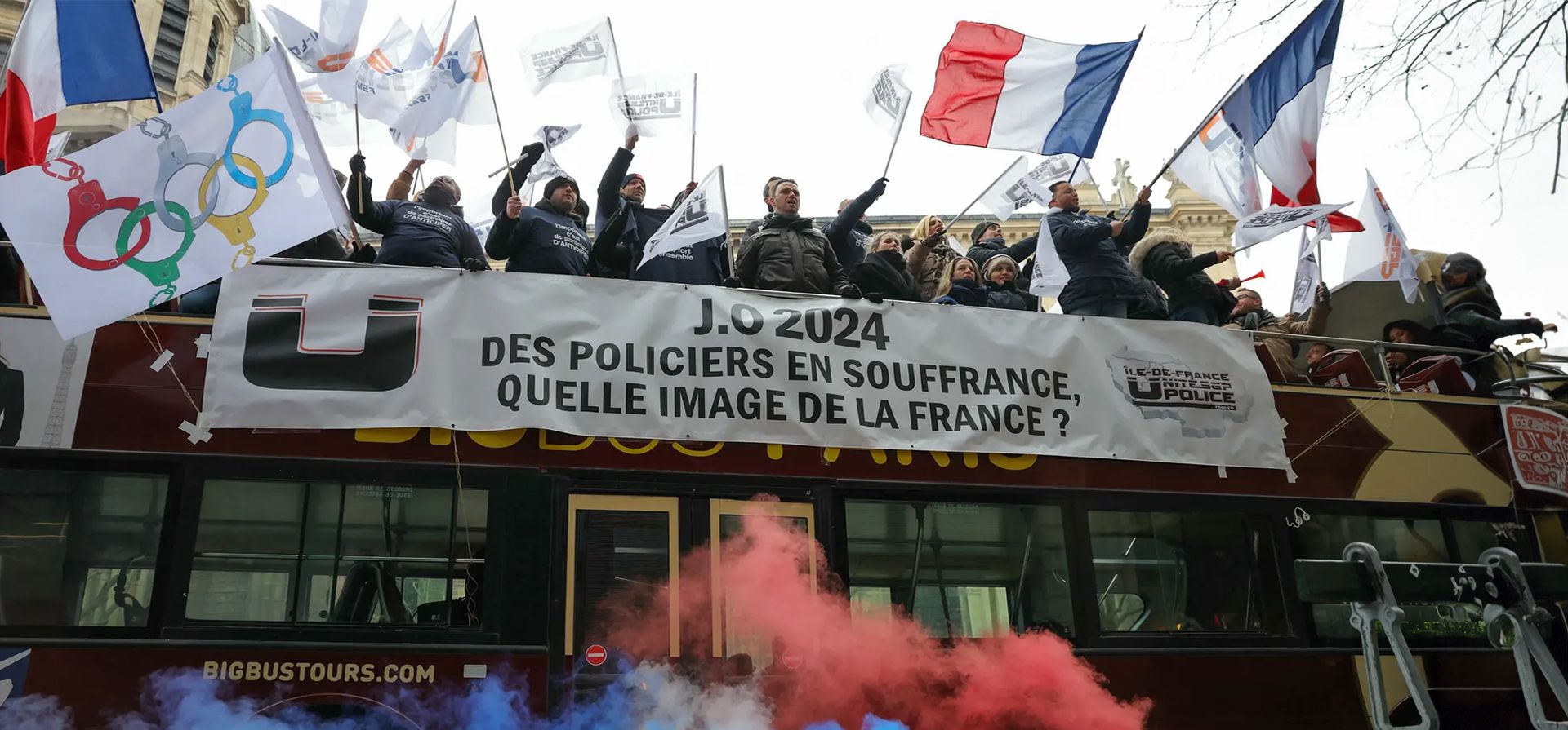 Agentes de policía ondean banderas en la parte superior de un autobús turístico con una pancarta en la que se lee "policías sufriendo, ¿qué imagen de Francia?" mientras participan en una manifestación sobre la falta de información sobre cómo asegurar los Juegos Olímpicos de París 2024., Francia. Fotografía: Thomas Samson/AFP/Getty Images Agentes de policía ondean banderas en la parte superior de un autobús turístico con una pancarta en la que se lee "policías sufriendo, ¿qué imagen de Francia?" mientras participan en una manifestación sobre la falta de información sobre cómo asegurar los Juegos Olímpicos de París 2024., Francia. Fotografía: Thomas Samson/AFP/Getty Images