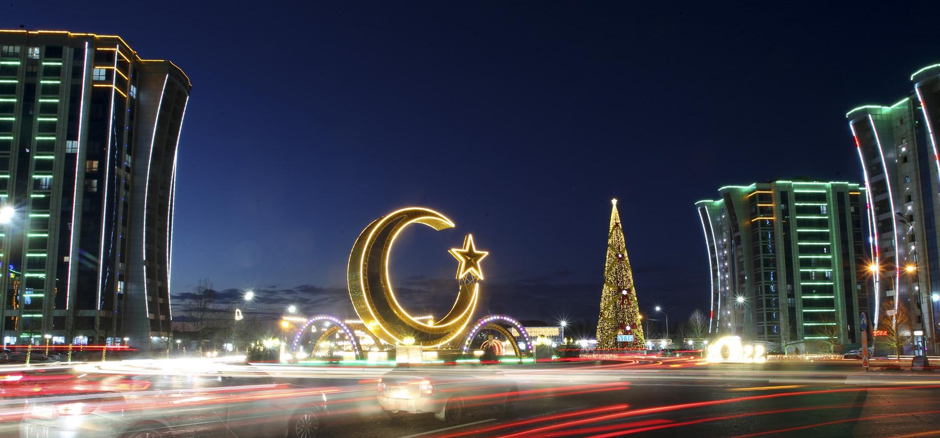 Una media luna y edificios de apartamentos decorados para las celebraciones de Año Nuevo se ven a través de una ventana que refleja una luz navideña en la plaza central de Argún, Chechenia, Rusia. Foto: AP