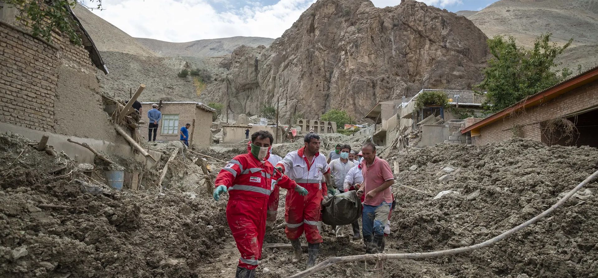 Miembros de la Cruz Roja y aldeanos que portan un cuerpo encontrado en las ruinas de una casa destruida después de inundaciones repentinas, Mazdaran, Irán. Fotografía: Morteza Nikoubazl/NurPhoto/Rex/Shutterstock  