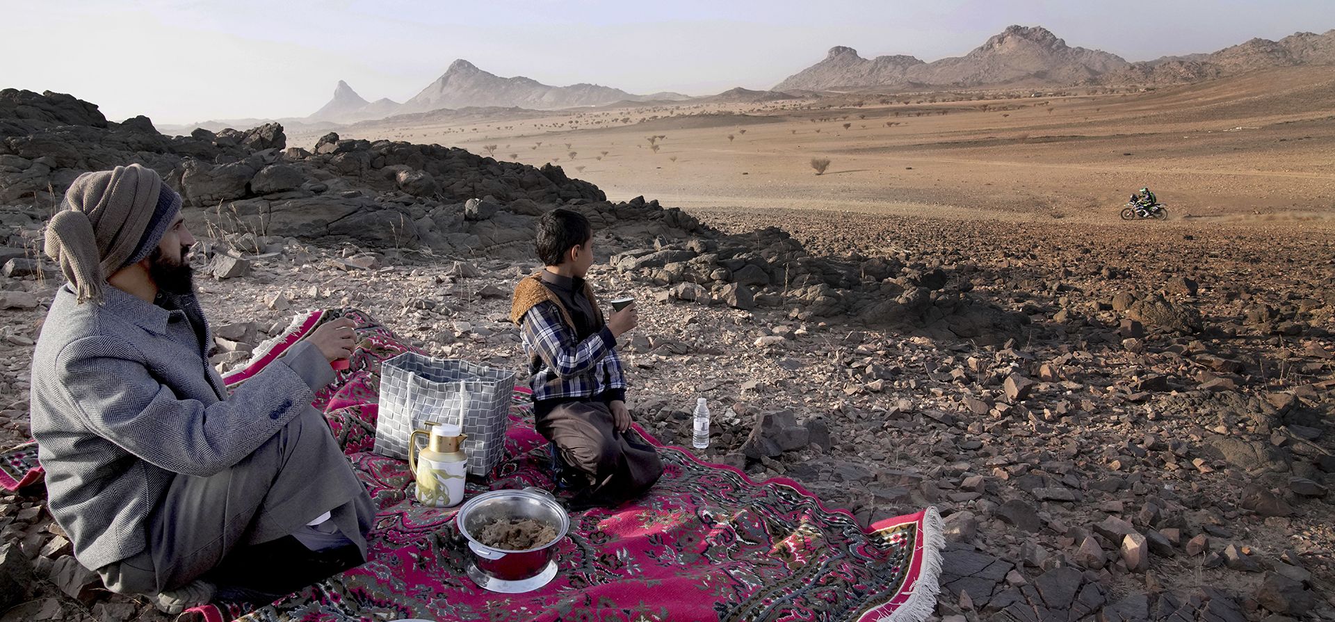 Un hombre y su hijo observan a los corredores durante el prólogo del Rally Dakar en Bisha, Arabia Saudita, el viernes 3 de enero de 2025. (Foto AP/Christophe Ena)