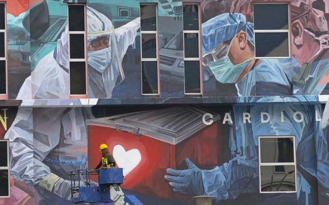 Un trabajador agrega los toques finales al gran tributo mural a los trabajadores de primera línea en la pandemia del coronavirus COVID-19 afuera de un hospital en Kuala Lumpur