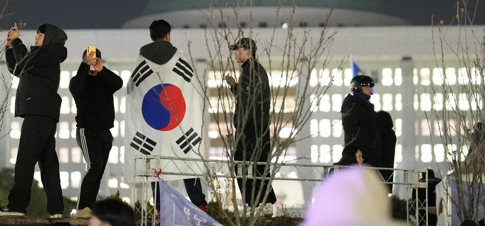 Un hombre con una bandera nacional se encuentra en el muro de la Asamblea Nacional en Seúl, Corea del Sur, el miércoles 4 de diciembre de 2024. (Foto AP/Lee Jin-man) Un hombre con una bandera nacional se encuentra en el muro de la Asamblea Nacional en Seúl, Corea del Sur, el miércoles 4 de diciembre de 2024. (Foto AP/Lee Jin-man)