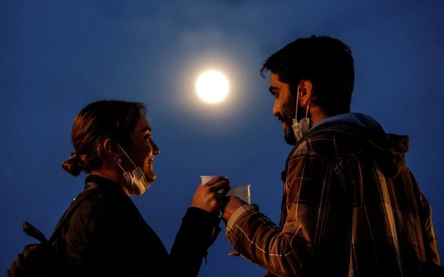 Una pareja toma una copa mirando la luna en el barrio de Trastevere en Roma