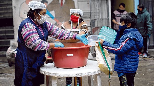 Asistencia. Un ni&ntilde;o entrega un recipiente para llevarse la comida en un barrio popular de Buenos Aires.