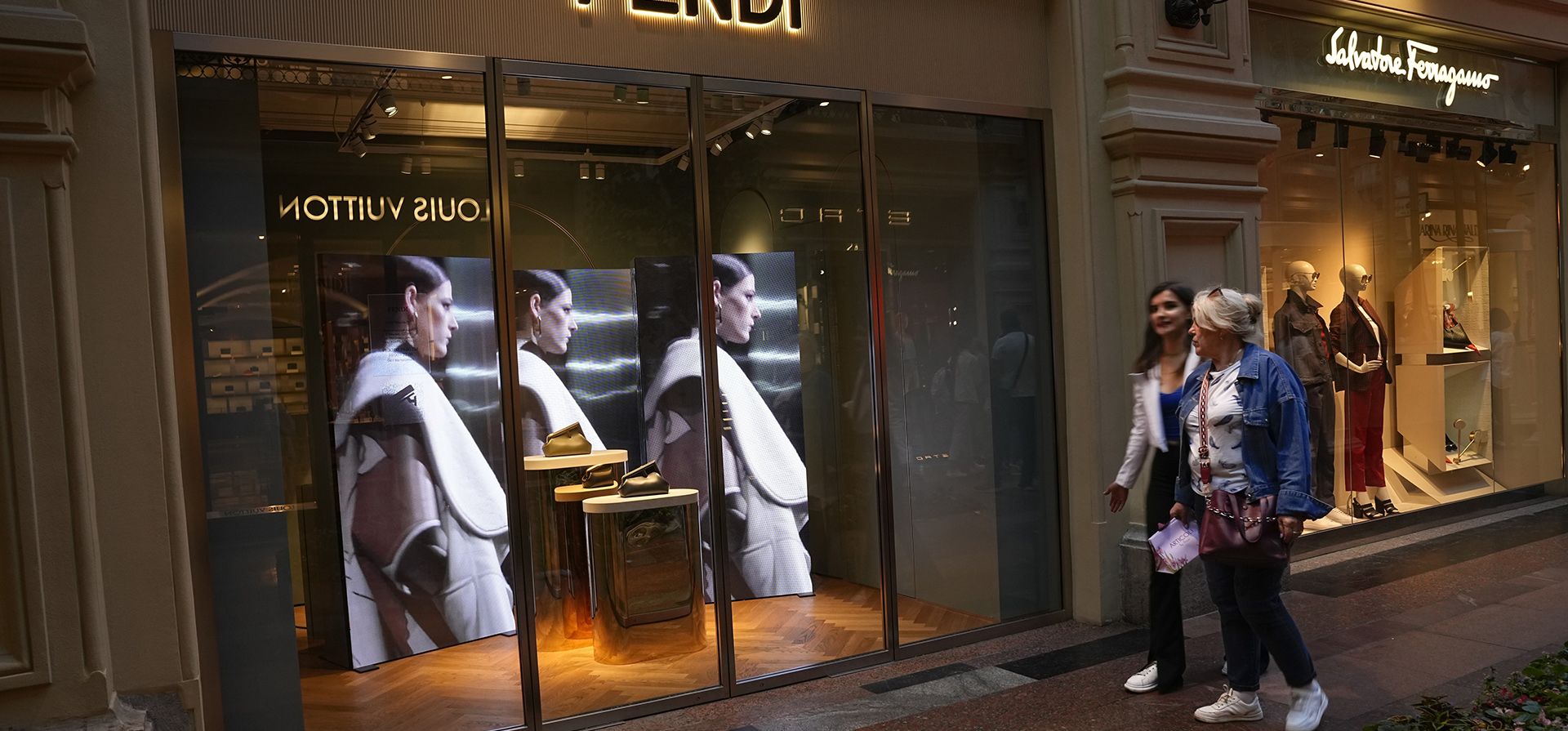 Dos mujeres pasan frente a una boutique Fendi cerrada debido a las sanciones en los grandes almacenes GUM en Moscú, Rusia, el martes 9 de agosto de 2022. A menudo, es difícil saber cuándo las tiendas están cerradas. En los famosos grandes almacenes GUM llenos de tiendas en la Plaza Roja, la mayoría de los escaparates cerrados aún tenían las luces encendidas y un empleado o guardia adentro.
