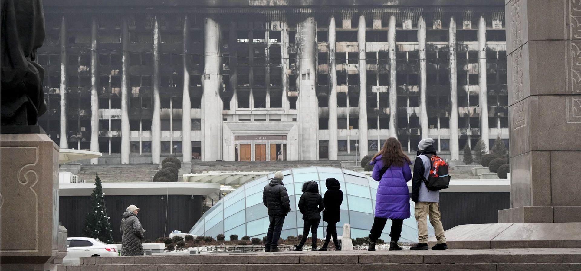 Gente observa el edificio del ayuntamiento en la plaza central bloqueada por las tropas y la policía de Kazajstán en Almaty, Kazajstán, el martes 11 de enero de 2022. Las autoridades de Kazajstán dicen que casi 8.000 personas fueron detenidas por la policía durante las protestas que desembocaron en violencia la semana pasada y marcó los peores disturbios que ha enfrentado la antigua nación soviética desde que obtuvo la independencia hace 30 años.