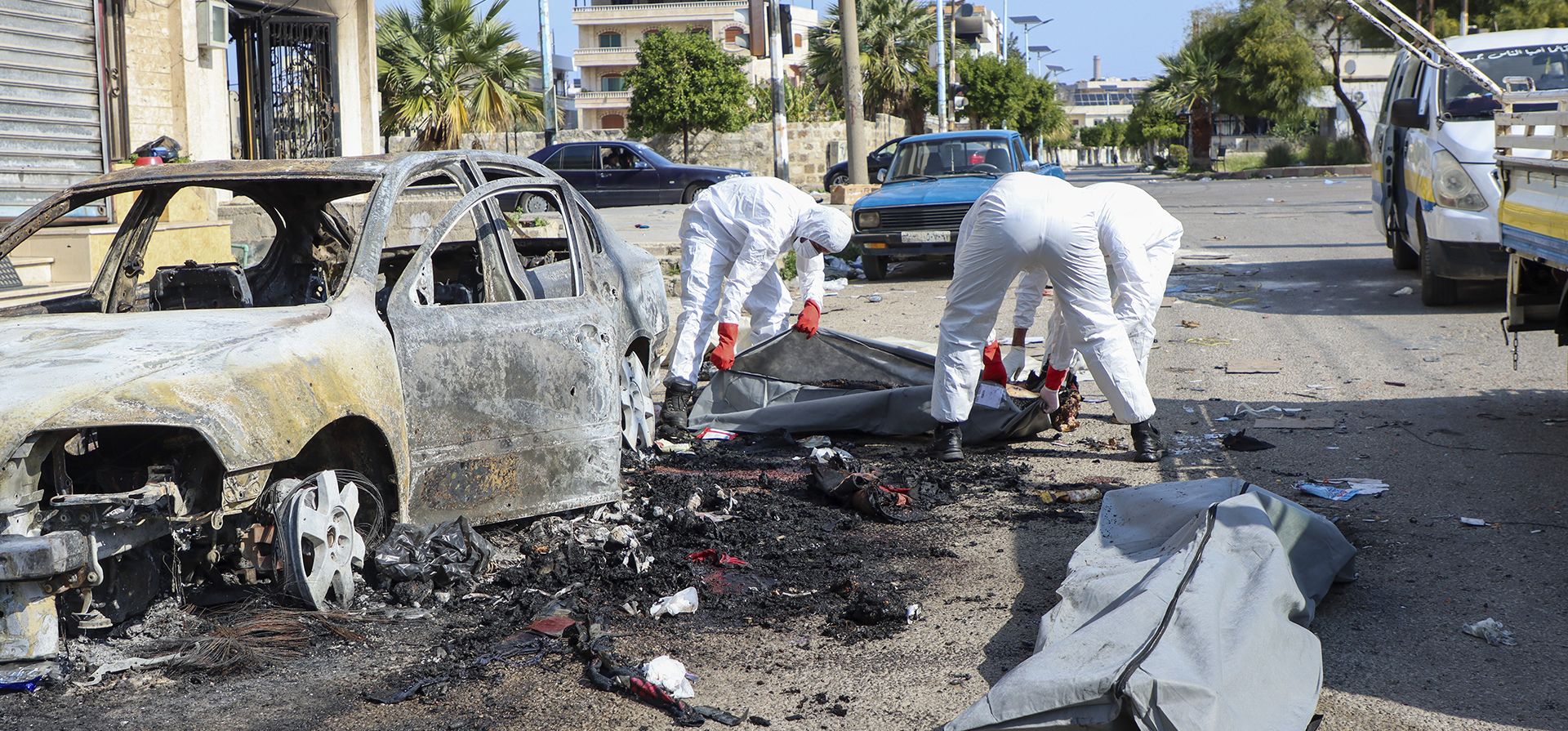 Miembros de la defensa civil de los Cascos Blancos sirios recogen los cuerpos de las personas que fueron encontradas muertas tras la reciente ola de violencia entre las fuerzas de seguridad sirias y hombres armados leales al expresidente Bashar Assad. (Cascos Blancos de Defensa Civil Siria vía AP)