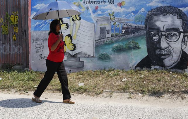 Una mujer pasa por delante de un mural que exhibe el rostro de Gabo García Márquez