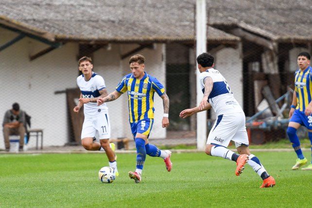 El volante central Lucas Ramos traslada frente a la doble marca de los futbolistas de Gimnasia.