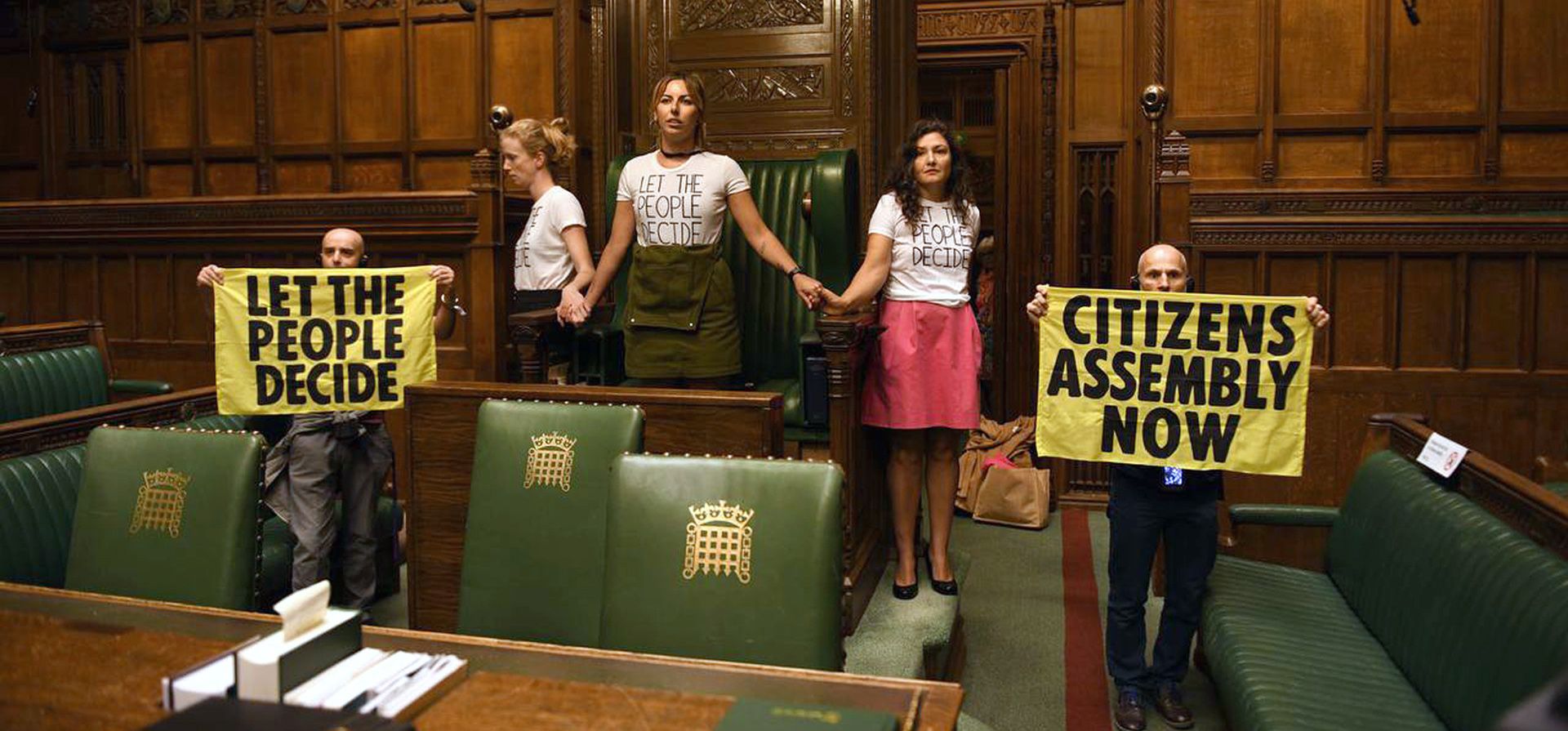 Activistas de Extinction Rebellion realizan una protesta en la cámara de la Cámara de los Comunes, el Parlamento británico, en Londres, el viernes 2 de septiembre de 2022. El grupo ambientalista Extinction Rebellion dijo el viernes que sus partidarios se han pegado unos a otros en una cadena alrededor de la silla utilizada por el orador en la cámara de la Cámara de los Comunes.