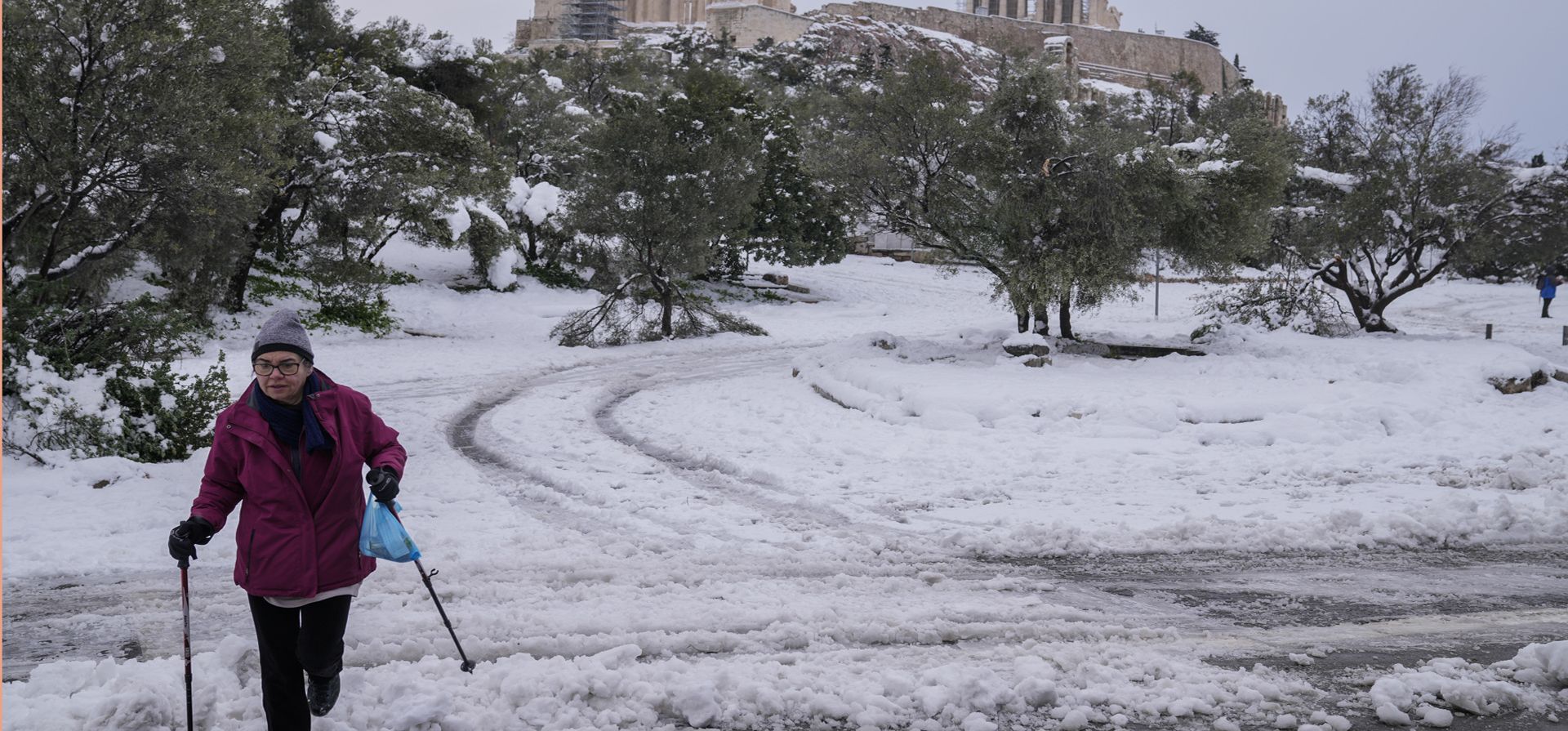 Una mujer con bastones de esquí camina sobre la nieve frente a la antigua colina de la Acrópolis, en Atenas. Una tormenta de nieve de gravedad interrumpió el tráfico aéreo y por carretera el lunes en la capital griega de Atenas y la vecina Turquía.