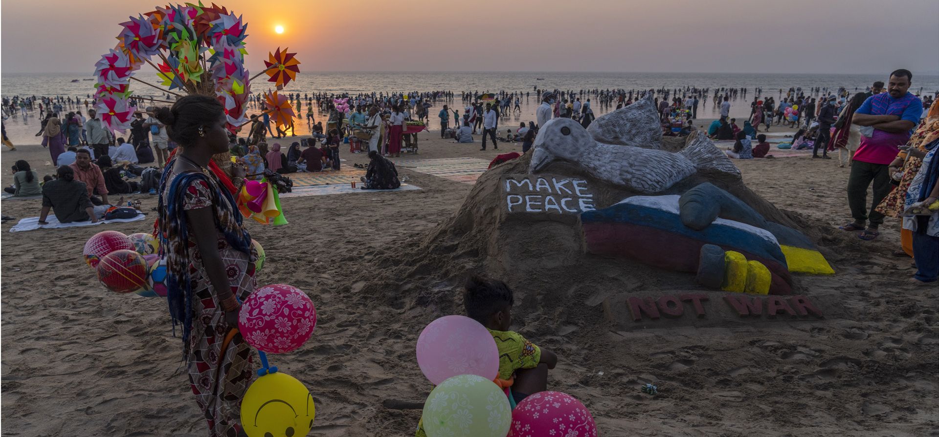 La gente mira una escultura de arena que pide la paz por la guerra entre Rusia y Ucrania en la playa de Juhu en Mumbai, India, el viernes 4 de marzo de 2022.