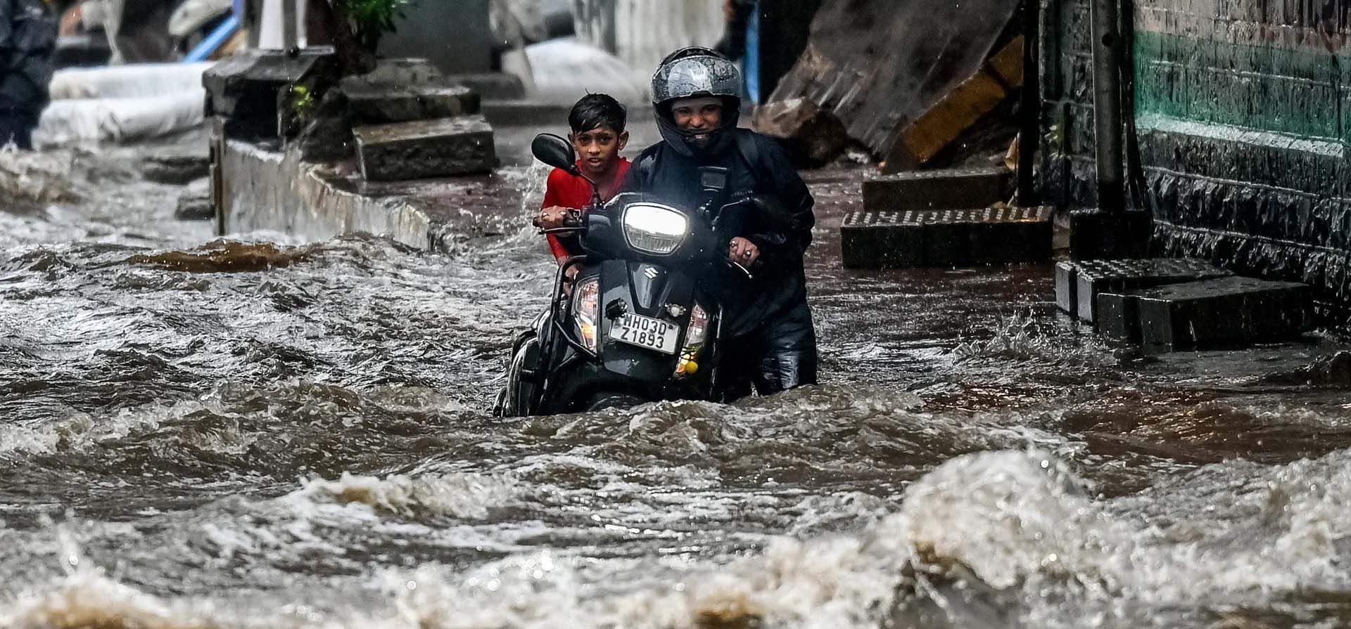 Un hombre empuja su ciclomotor por una calle inundada después de una fuerte lluvia, Mumbai, India. Fotografía: Punit Paranjpe/AFP/Getty Images Un hombre empuja su ciclomotor por una calle inundada después de una fuerte lluvia, Mumbai, India. Fotografía: Punit Paranjpe/AFP/Getty Images