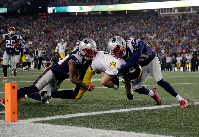 Fricción. Jugadores de New England Patriots tratan de impedir el avance de un rival.