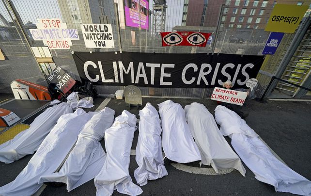 Activistas climáticos simulan cadáveres envueltos con paños blancos protestan cerca de la sede de la Cumbre del Clima de la ONU COP26 en Glasgow, Escocia, el jueves 11 de noviembre de 2021.