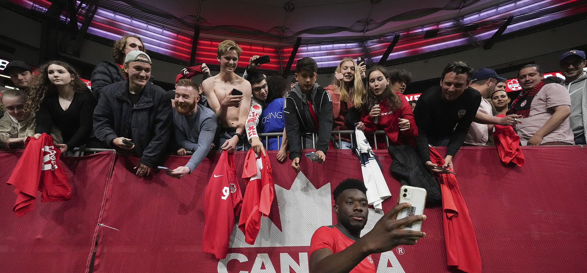 El canadiense Alphonso Davies posa para selfies con los fanáticos después de que Canadá derrotó a Curazao durante un partido de fútbol de la Liga de Naciones CONCACAF  en Vancouver.