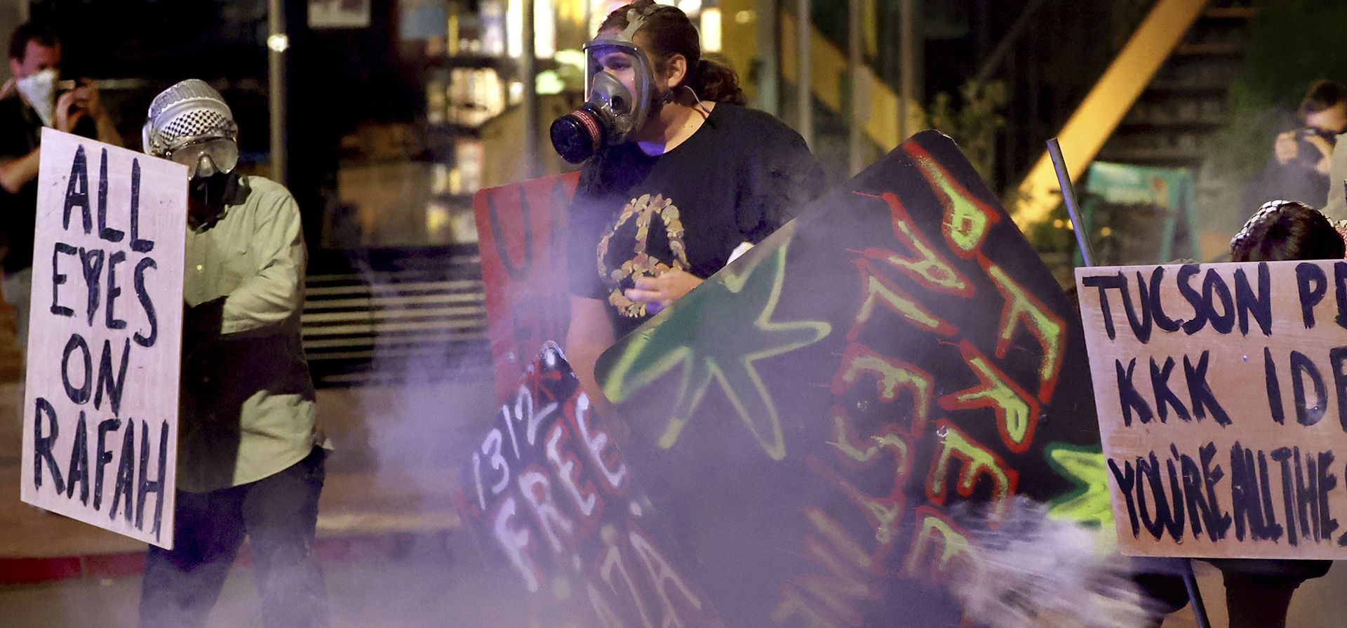 Los manifestantes se retiran a lo largo de University Boulevard en una nube de gases lacrimógenos mientras los agentes del orden utilizan municiones químicas para despejar un campamento fuera del campus de la Universidad de Arizona, el viernes 10 de mayo de 2024, Tucson, Az. (Kelly Presnell/Arizona Daily Star vía AP) Los manifestantes se retiran a lo largo de University Boulevard en una nube de gases lacrimógenos mientras los agentes del orden utilizan municiones químicas para despejar un campamento fuera del campus de la Universidad de Arizona, el viernes 10 de mayo de 2024, Tucson, Az. (Kelly Presnell/Arizona Daily Star vía AP)