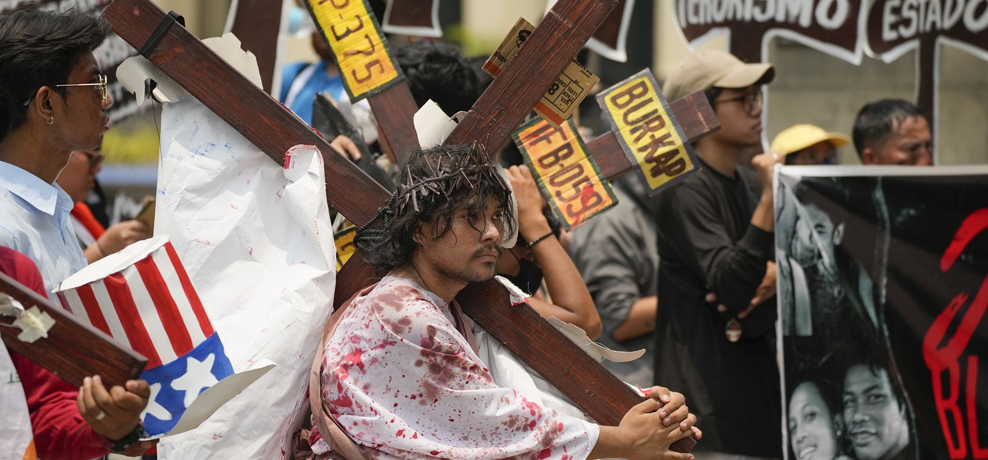 Un activista lleva una cruz de madera mientras recrean los sufrimientos de Jesucristo durante una protesta de Semana Santa en Manila, Filipinas, el lunes 3 de abril de 2023. El grupo se reunió para crear conciencia sobre las dificultades que sufre la gente cuando comienza la Semana Santa en este país predominantemente católico. (Foto AP/Aarón Favila)