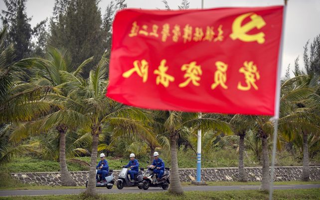 Trabajadores transitan en motos una carretera del centro espacial Wenchang en Wenchang