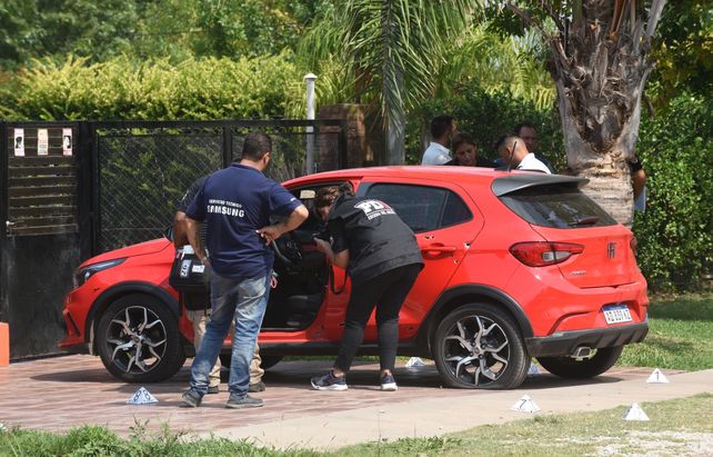 Efectivos de la Agencia de Investigación Criminal levantan rastros del auto de la mujer baleada.