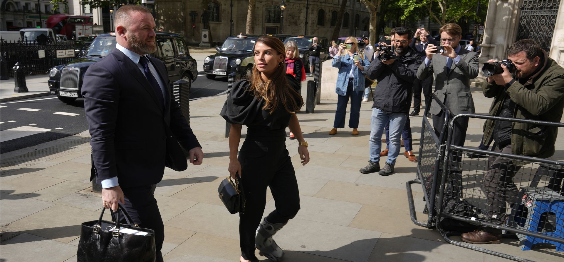 Coleen Rooney mira a su esposo, el exjugador de fútbol de Inglaterra Wayne Rooney, llegan juntos al Tribunal Superior de Londres, el jueves 12 de mayo de 2022. Se abrió un juicio que involucra una disputa en las redes sociales entre dos cónyuges de futbolistas en Londres. Rebekah Vardy demandó por difamación después de que Coleen Rooney la acusó de compartir sus publicaciones privadas en las redes sociales con el periódico The Sun.