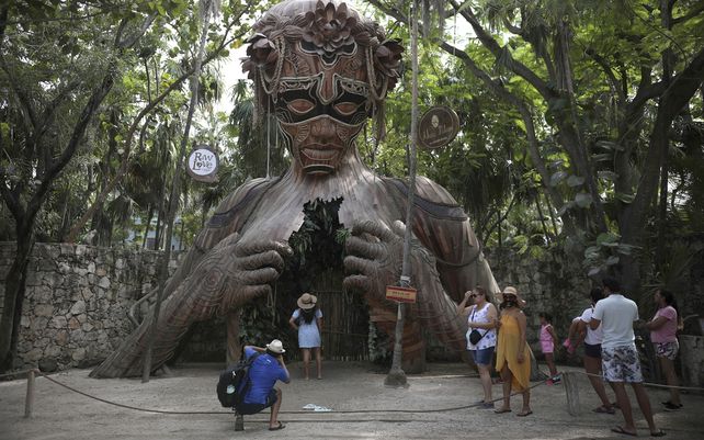 Turistas esperan turno para posar con una escultura figurativa que sirve como arco del artista sudafricano Daniel Popper titulada Ven a la Luz en el resort Ahau Tulum