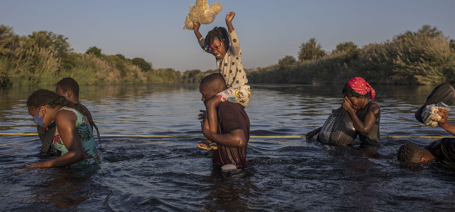 Una niña sostiene su peluche por encima del agua mientras migrantes, muchos de ellos de Haití, cruzan el río Bravo desde Del Río, Texas, para regresar a Ciudad Acuña, México, para evitar la deportación. Estados Unidos transportaba a haitianos acampados en una ciudad fronteriza de Texas de regreso a su tierra natal y bloqueaba el paso de otros a cruzar la frontera desde México. (Foto AP)