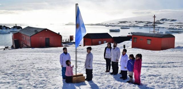 Alumnos y maestros izan la bandera Argentina en la escuela de la Antártida. 