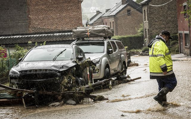 Un hombre camina junto a automóviles dañados en una calle inundada en Mery