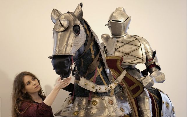 Un empleada de Bonhams mira un conjunto de armadura completa ecuestre de estilo alemán de finales del siglo XVI para un hombre y un caballo