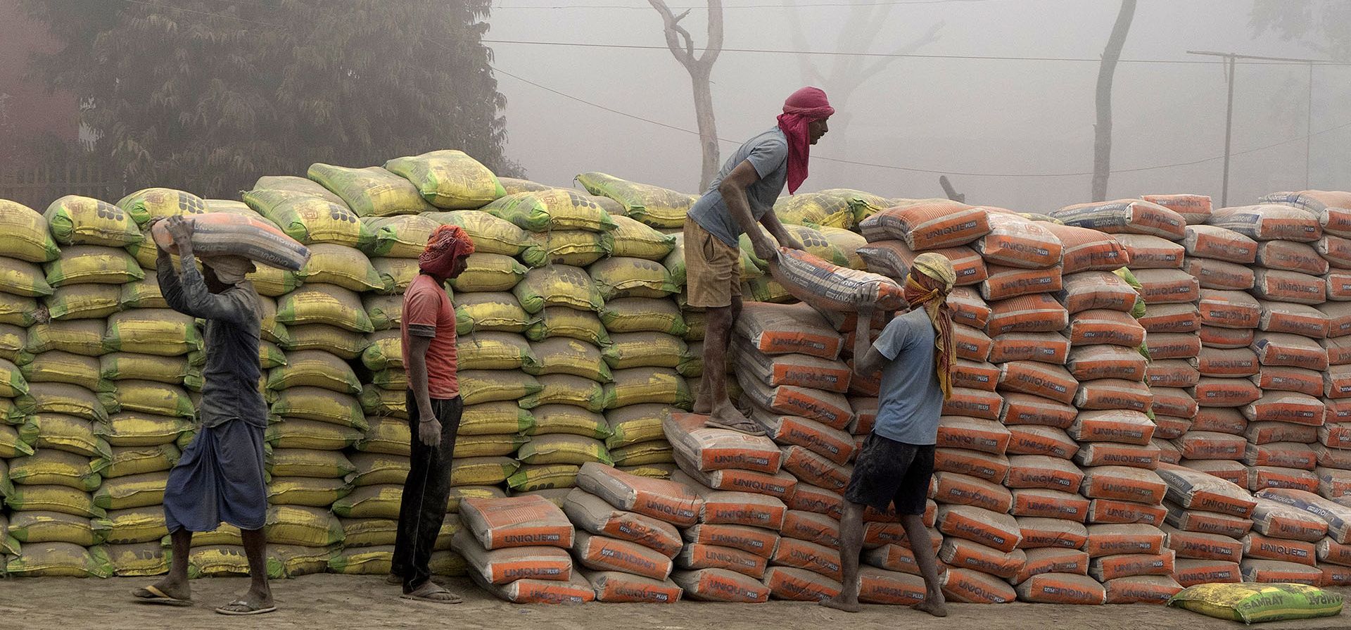 Los trabajadores cargan sacos de cemento en un camión en medio de la niebla matutina cerca de la estación de tren de Buxar en el estado norteño de Bihar, India. Miércoles, 21 de diciembre de 2022. (Foto AP/Rajesh Kumar Singh)
