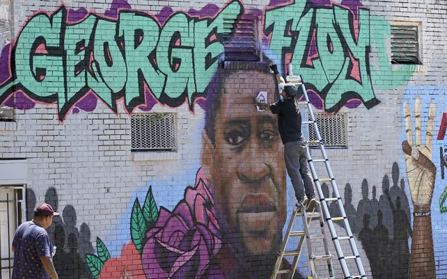 Un joven pinta un mural en honor a George Floyd