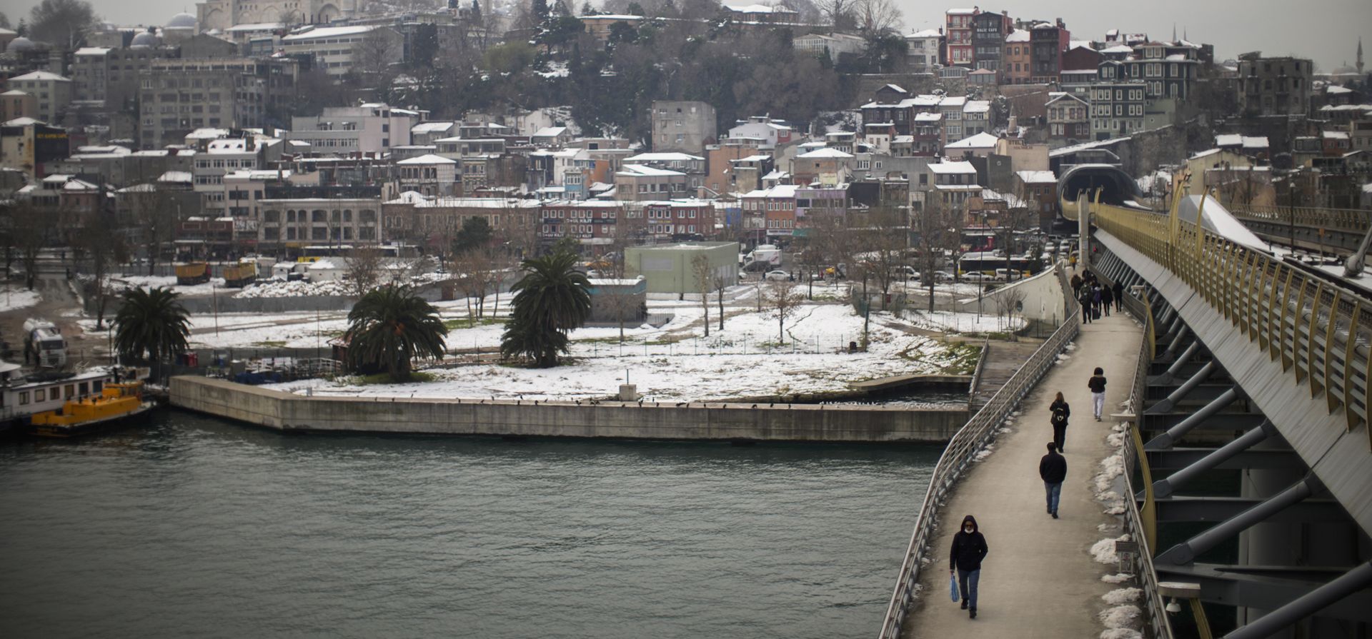 Peatones cruzan el puente del metro Golden Horn parcialmente cubierto de nieve cerca de la mezquita de Suleymaniye, en Estambul, Turquía, el 27 de enero de 2022. El tráfico por carretera y aéreo estaba volviendo a la normalidad, pero la nieve aún cubría grandes franjas de la metrópoli de 16 millones de personas.