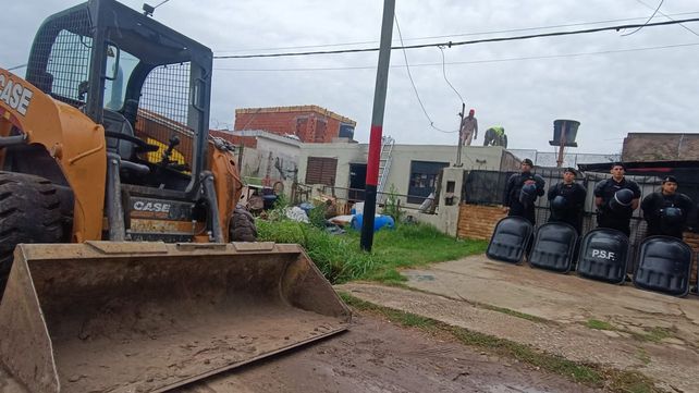 Pala mecánica lista y custodia policial en los trabajos de derrumbe de un búnker de venta de drogas en la zona oeste