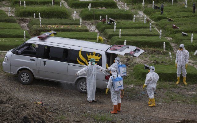 Un trabajador rocía a un compañero con desinfectante después del entierro de una persona que presuntamente murió por coronavirus en un cementerio en Medan, Sumatra del Norte, Indonesia.