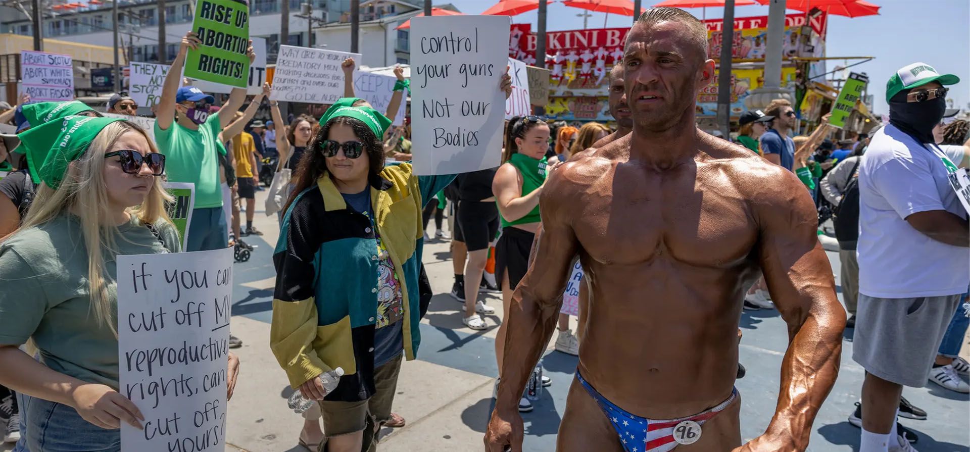 Mattias Lietgeb, de Austria, espera los resultados de un concurso de culturismo en Muscle Beach en Venecia mientras pasa entre los manifestantes que denuncian la decisión de la Corte Suprema que anula el histórico caso Roe v Wade, eliminando el derecho federal a un aborto. Fotografía: David McNew/Getty Images