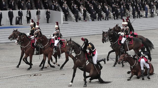 Dos guardias republicanos recuperan el control de sus caballos después de caer durante el desfile anual del Día de la Bastilla en los Campos Elíseos en París.