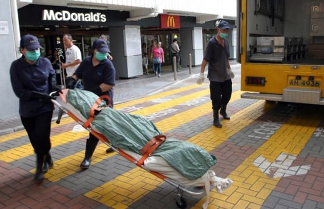 La mujer es retirada sin vida del local de comidas rápidas. (image: South China Morning Post)