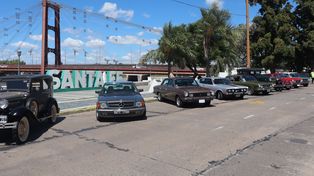 Vehículos históricos durante la entrega de matrículas en la capital provincial, con el puente colgante como marco de la actividad.