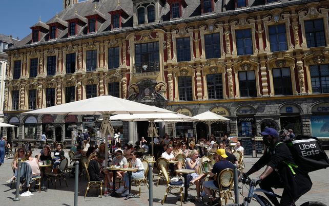 La gente disfruta de una comida en un restaurante con terraza durante la reapertura nacional de locales gastronómicos