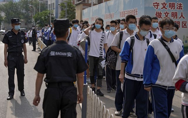 Guardias de seguridad controlan a los estudiantes con máscaras faciales para ayudar a frenar la propagación del coronavirus