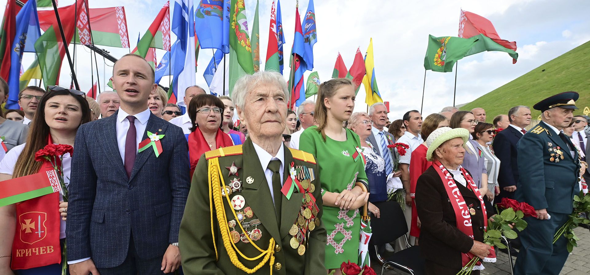 La gente canta el himno nacional mientras participa en una ceremonia de ofrenda floral en el Monumento al Montículo de la Gloria durante la celebración del Día de la Independencia de Bielorrusia, en las afueras de Minsk, Bielorrusia, el domingo 3 de julio de 2022.