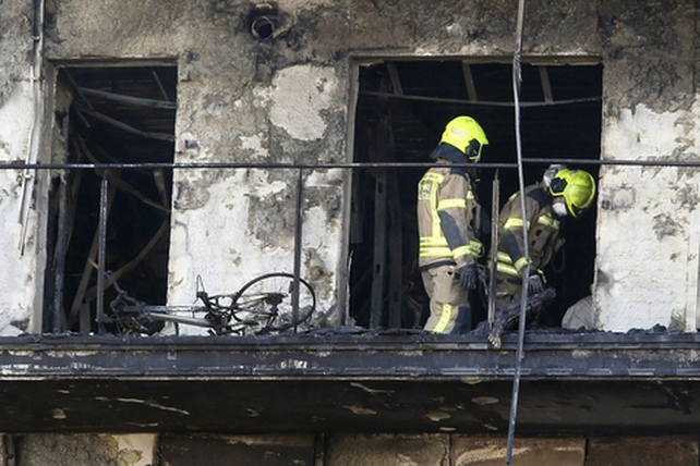Dos bomberos junto a un cad&aacute;ver totalmente carbonizado en un balc&oacute;n. 