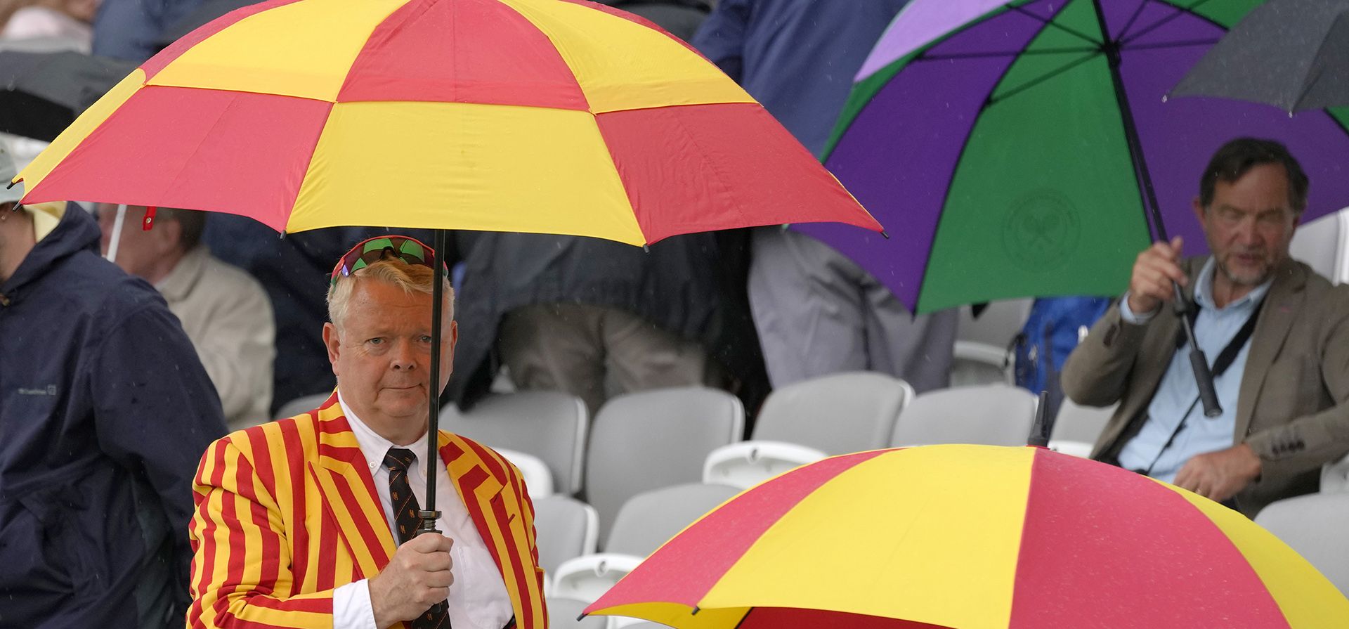 El público hace uso de sus paraguas mientras la lluvia detiene el juego durante el primer día del partido de prueba entre Inglaterra y Sudáfrica en el campo de cricket Lord