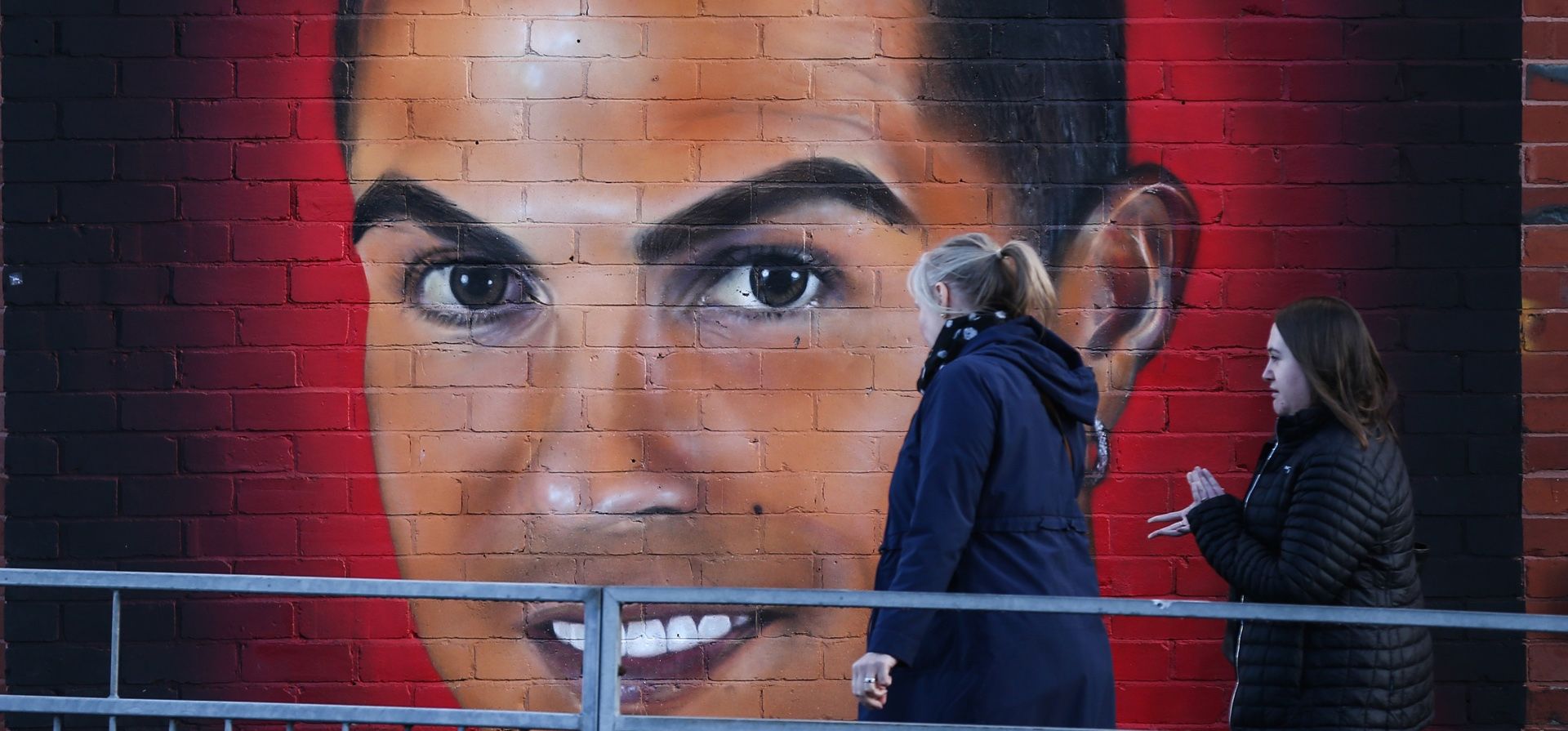 La gente pasa frente a un mural del exjugador del Manchester United, Cristiano Ronaldo, cerca de Old Trafford en Manchester, Gran Bretaña, el 23 de noviembre de 2022. Los propietarios del Manchester United, la familia Glazer, emitieron un comunicado en el que decían que 