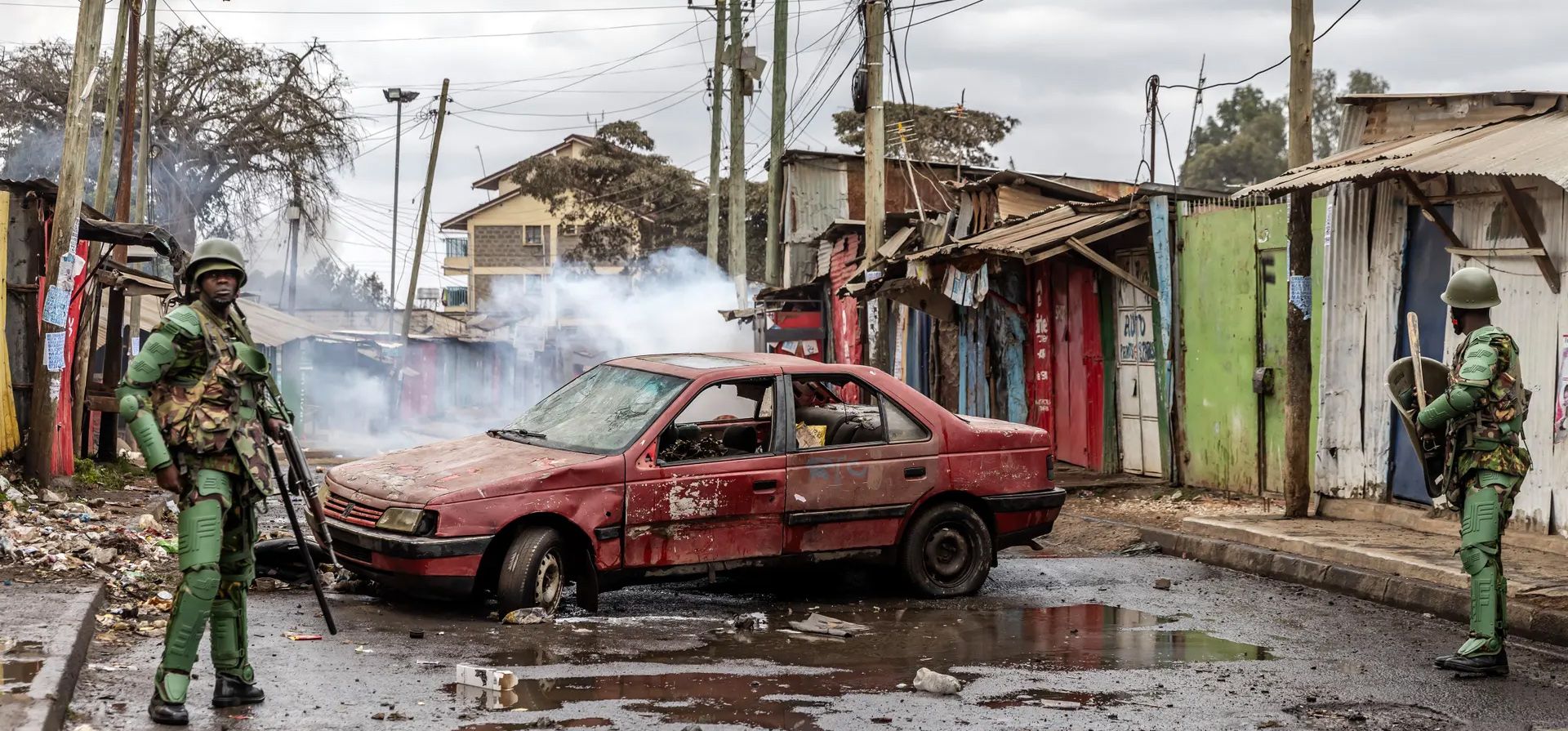 Nairobi, Kenia. Agentes de policía patrullan junto a un automóvil destrozado que ha sido utilizado como barricada por partidarios de la oposición durante las protestas contra el gobierno. Fotografía: Luis Tato/AFP/Getty Images Nairobi, Kenia. Agentes de policía patrullan junto a un automóvil destrozado que ha sido utilizado como barricada por partidarios de la oposición durante las protestas contra el gobierno. Fotografía: Luis Tato/AFP/Getty Images