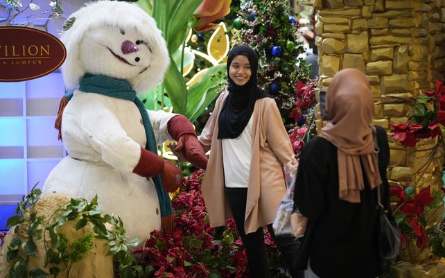 Una mujer toma una foto con un teléfono móvil en un centro comercial con adornos navideños en Kuala Lumpur, Malasia, el miércoles 8 de diciembre de 2021. Los mercados de valores del Sudeste Asiático cerraron con fuertes caídas arrastrados por los temores generados por la nueva variante del coronavirus detectada en el sur de África.