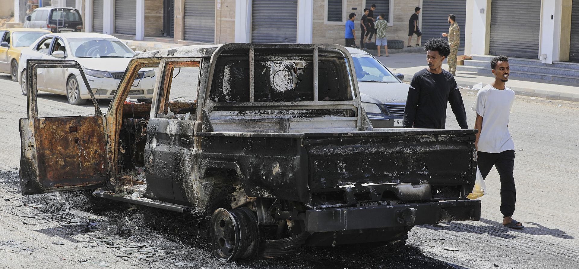 Libios pasan junto a un vehículo incendiado tras los enfrentamientos del lunes por la noche entre milicias armadas en Trípoli, Libia, el martes 13 de mayo de 2025. (Foto AP/Yousef Murad) Libios pasan junto a un vehículo incendiado tras los enfrentamientos del lunes por la noche entre milicias armadas en Trípoli, Libia, el martes 13 de mayo de 2025. (Foto AP/Yousef Murad)