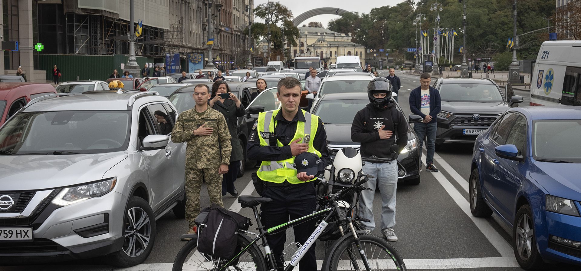 Un policía y conductores observan un minuto de silencio a nivel nacional en memoria de los soldados caídos que defendieron su patria en la guerra con Rusia, en el Día de los Defensores en el centro de Kiev, Ucrania, el martes 1 de octubre de 2024. (Foto AP/Efrem Lukatsky)