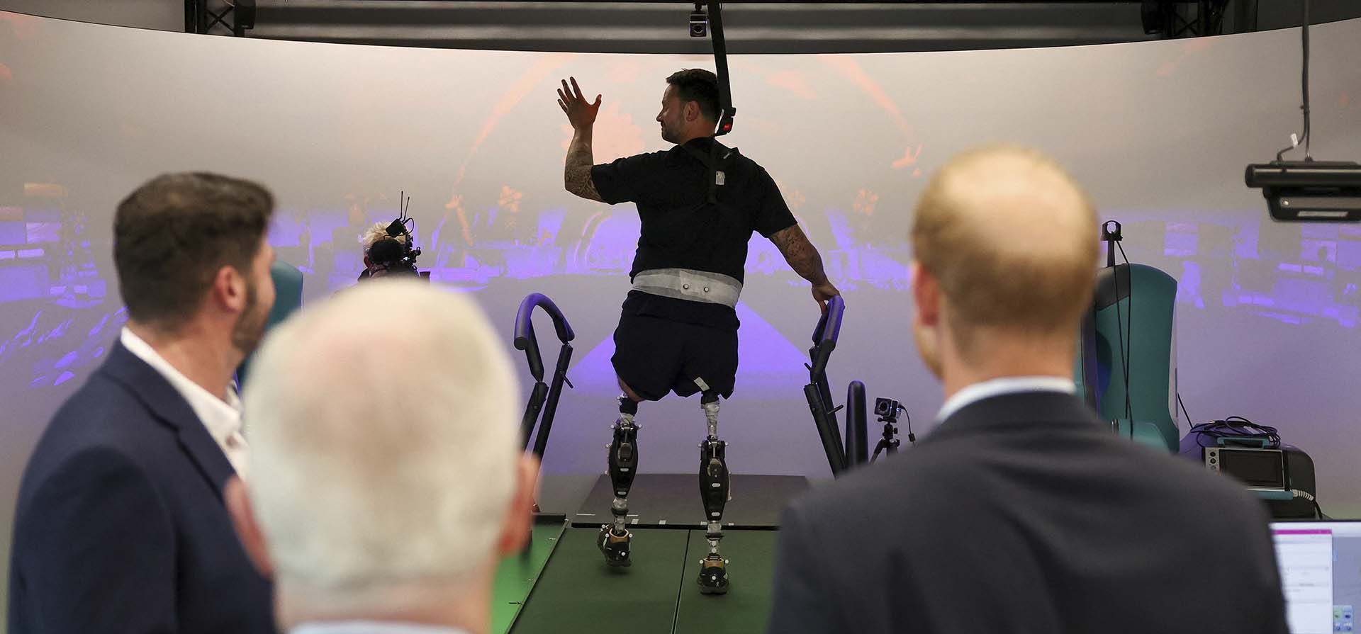 El príncipe Harry de Gran Bretaña observa a Steve Arnold, quien ha competido en los Juegos Invictus, mientras camina en el laboratorio de trabajo de marcha durante una visita al Centro de Estudios de Lesiones por Explosión en el Imperial College de Londres, en Londres, el miércoles 10 de septiembre de 2025. (Suzanne Plunkett, Pool Photo vía AP)